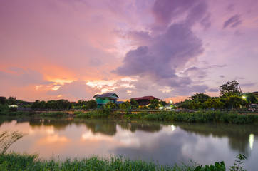 Sunset on twilight with wooden house near river.