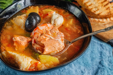 Seafood soup, salmon and cod with potatoes. Served with lemon and olives. Close up