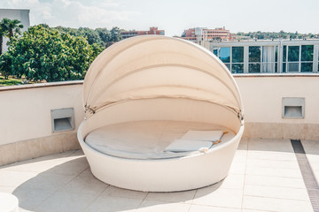 White outdoor furniture round rattan sofa with cushions, a place to relax on the terrace of the...