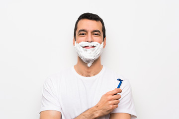 Man shaving his beard over isolated white background keeping the arms crossed in frontal position
