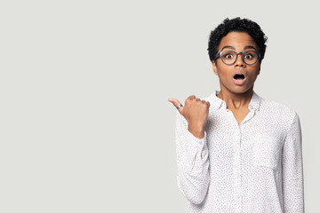 Head shot shocked African American woman pointing finger to aside
