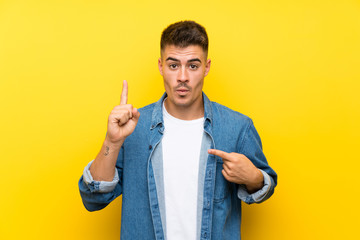 Young handsome man over isolated yellow background with surprise facial expression
