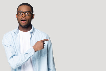Surprised African American man with open mouth pointing to aside