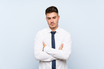 Handsome businessman over isolated blue background keeping arms crossed