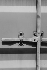 Detail of a typical shipping container locking system, showing the upper part of the container against a factory building.