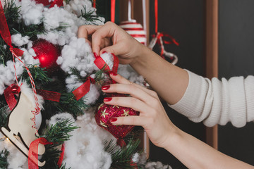 Young woman decorating Christmas tree with red ball