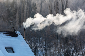 Smoke from the chimney of a house at dawn of the sun