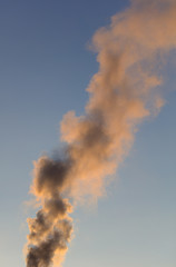Smoke from the chimney of a house at dawn of the sun