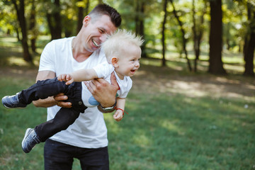 Fototapeta premium Young father plays with the child in the park.