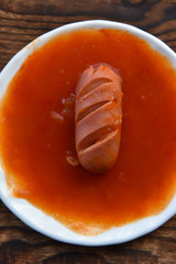 hot sausages with cuts in tomato sauce