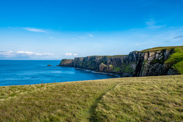 Saftige Weiden unter blauem Himmel an der Küste der Isle of Skye