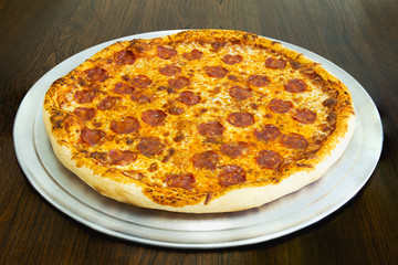 Fresh pepperoni pizza on woooden table in restaurant.