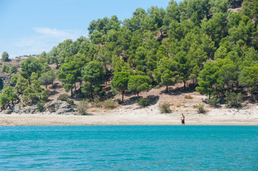 Man going to plunge into the lake. Sunny day on a lake with turquoise water. Summer vacations. Water reservoir in Spain. Embalse del conde de guadalhorse.