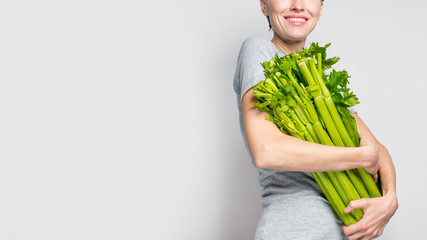  Woman holding green fresh celery. Healthy eating, vegetarian food, dieting and people concept
