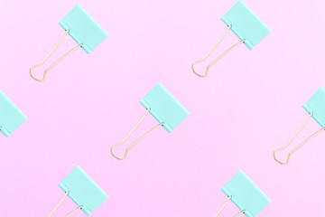 Abstract background. Pattern made of turquoise clips for papers on a pink background. Flat lay style. Background for business and education.