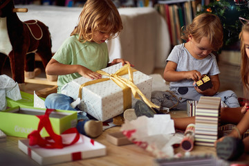 Children opening Xmas presents. Kids under Christmas tree with gift boxes.