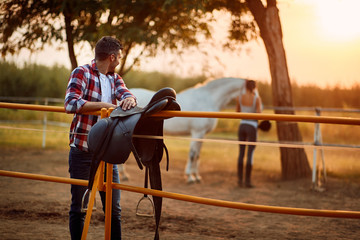man with horse at  ranch.Saddling a horse.