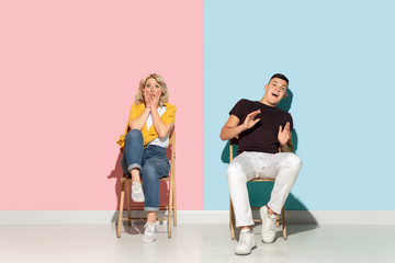 Fototapeta na wymiar Young emotional man and woman in bright casual clothes posing on pink and blue background. Concept of human emotions, facial expession, relations, ad. Beautiful caucasian couple shocked, scared