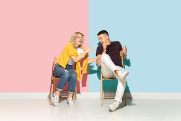 Young emotional man and woman in bright casual clothes posing on pink and blue background. Concept of human emotions, facial expession, relations, ad. Beautiful caucasian couple shocked, scared