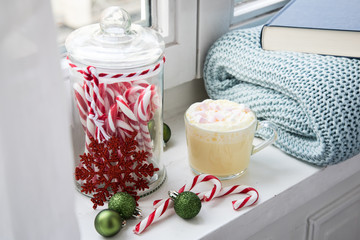 Heiße, weiße Trinkschokolade mit Sahne und Marshmellows Fensterbank mit gemütlicher Wolldecke und Buch am Weihnachten Advent Wochenende