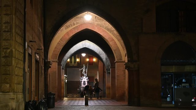 Bologna, Italy - October 2019 - Unknown people walk in the evening among the buildings and monuments of the historic city center, followed by the shadows of the night
