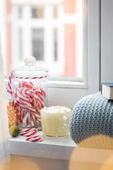 Heiße, weiße Trinkschokolade mit Sahne und Marshmellows Fensterbank mit gemütlicher Wolldecke und Buch am Weihnachten Advent Wochenende mit Bokeh