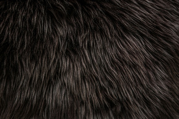 abstract background of warm artificial dark brown fur on a knitted base close up