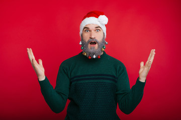 Fototapeta na wymiar Young man with white and decorated beard in christmas mod making surprised gesture