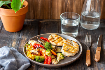 Grilled chicken with grilled vegetables on a wooden background. Healthy eating.