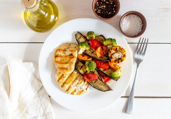 Grilled chicken with grilled vegetables on a wooden background. Healthy eating.
