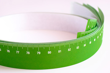 Meter tape for measuring rolled into a roll, on a light background. Selective focus.