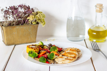 Grilled chicken with grilled vegetables on a wooden background. Healthy eating.