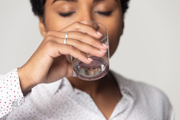 Thirsty African American girl drinking clean mineral water close up