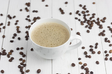 expresso coffee in a white mug on a white wooden background coffee beans around sugar and sweets