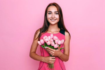 Obraz na płótnie Canvas l gentle young woman in dress with spring flowers on pink background. Women's day