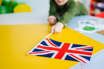 Young girl is holding Union Jack flag. British flag on the front view. Blurred background. Closeup.