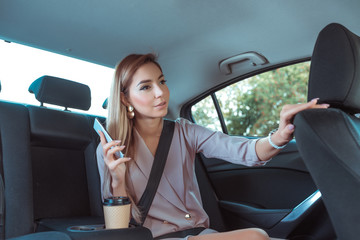 Beautiful woman in car passenger, asks driver to stop on arrival. Business VIP taxi rental car sharing in city. Summer girl in autumn city. Mobile phone internet taxi application.