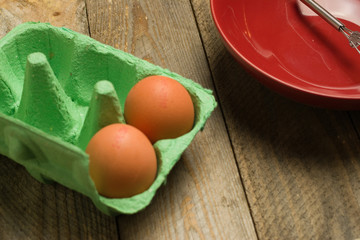  Eggs and whisk and red bowl on wooden background