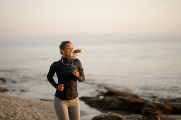 Fototapeta na wymiar Young happy athletic woman jogging at the beach.