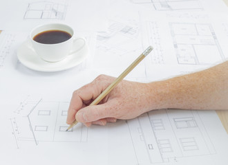 Architectural background. Human hand with pencil over blueprints with sketches of projects