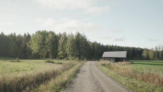 Path in the middle of two fields, wooden house in rigth side. 
Direction to forest.