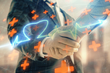 Double exposure of heart drawing on city view background with handshake. Concept of medical...