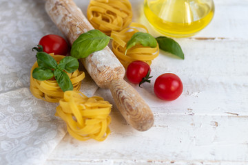 Ingredients for cooking Italian pasta. Pasta, basil, cheese, cherry tomatoes, olive oil, egg, yolk. On a light background. Copy space. 