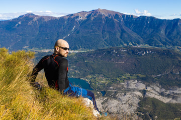 Fototapeta na wymiar Traveler man sitting on a hill of beautiful alpine landscape