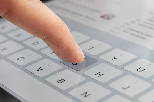 macro of a finger typing text on the touch screen keyboard of mobile device