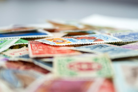 Closeup view on a variety of multi-colored postage stamps from different countries and years. Selective focus