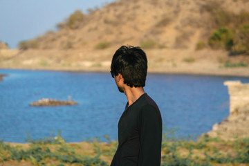 Naklejka na ściany i meble Indian male standing besides the lake