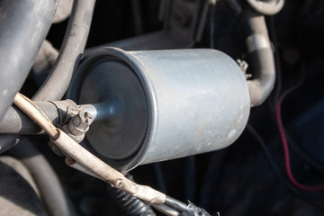 A closeup view of a fuel filter installed in a car with a fuel line connected to it. Filter element...