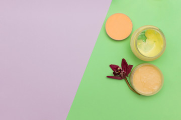 Cosmetic creams flat lay on colored background.