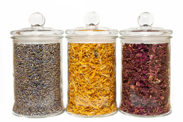 Three glass jars with flower dry petals of rose, lavender and calendula with caps